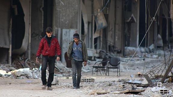 Dos jóvenes pasean entre los escombros de Damasco. 