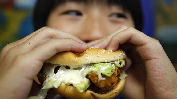 Una mujer se come una hamburguesa. 