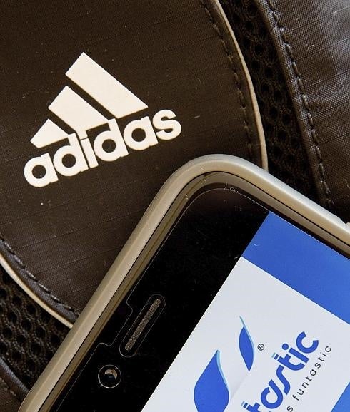 El logotipo de Adidas, junto a un móvil que muestra la aplicación deportiva Runtastic. 