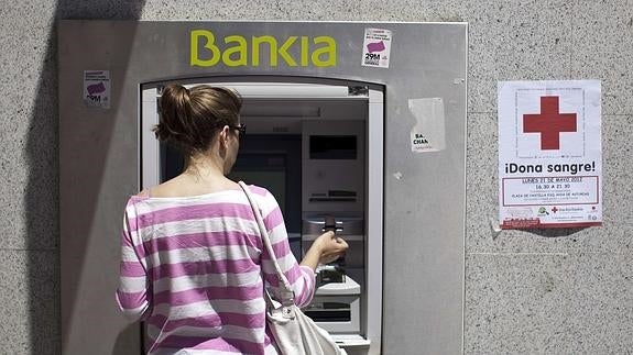 Una mujer sacando dinero de un cajero. 