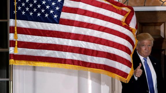 Donald Trump posa tras una bandera de Estados Unidos.