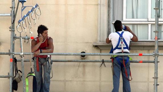 Dos trabajadores descansan en un andamio.