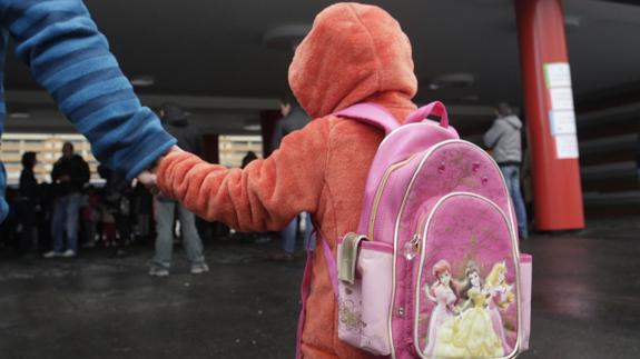 Una niña camina de la mano de un adulto. 