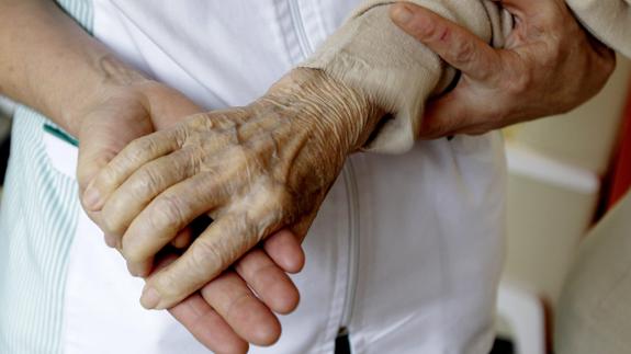 Una cuidadora ayuda a una mujer en un centro de Alzheimer. 