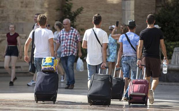 Cuatro jóvenes caminan con su maletas. 