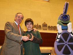 Ricardo Gómez entrega la medalla Lumière a Rafael Encinas, de Caja Segovia, en presencia de la mascota 'Cinecito'.