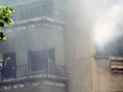 Un bombero (i) intenta entrar en la vivienda que ha sufrido un incendio en el centro de Soria. / EFE