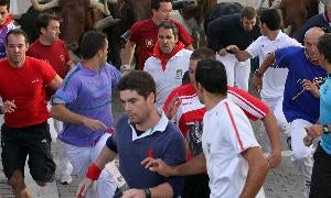 Alexander Fiske-Harrison, en primer plano, con el 'Financial Times' en la mano, corre delante de los toros, la semana pasada en Cuéllar. / A. TANARRO