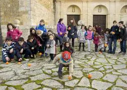 Niños de Carrión 'ruedan' las naranjas, a la puerta de la iglesia de Santa Clara. / GRAND