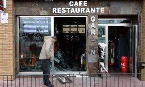 Un policía de paisano observa la tapa de alcantarilla que utilizaron los ladrones para romper la luna del bar Garden. / R. Otazo