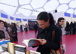 Una mujer ojea un libro durante la pasada edición de la Feria del Libro de Valladolid, realizada también en la Cúpula del Milenio / R. Gómez