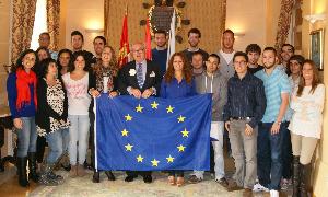 El grupo de jóvenes que han obtenido las becas Leonardo, ayer con el concejal de Empleo, Javier Giráldez, y la bandera de Europa. / EL NORTE