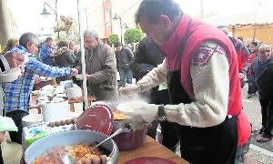Unos voluntarios reparten las raciones de guiso entre los asistentes./ Merche de la Fuente
