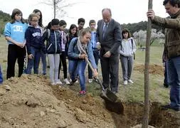 Javier León de la Riva ayuda a una escolar a plantar un árbol./ R. Otazo