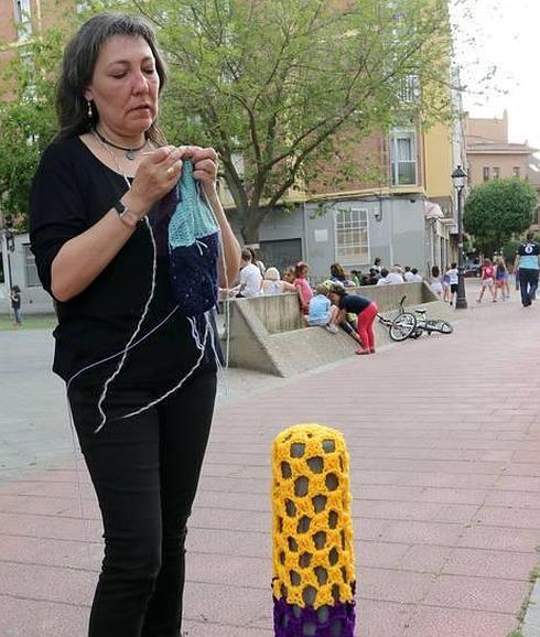 Una de las integrantes de Tejiendo en morado junto a un bolardo con ganchillo. 