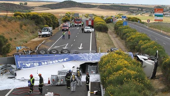 Guardia Civil y técnicos, junto al camión volcado sobre los carriles y el arcén de la autovía.