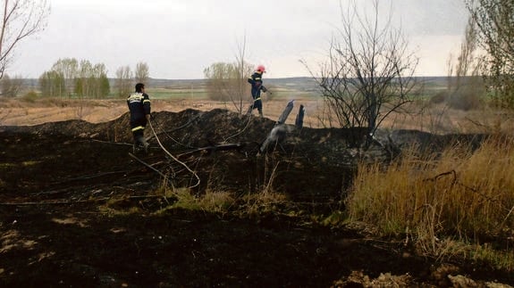 Dos bomberos voluntarios extinguen un incendio.