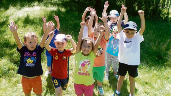 Un grupo de niños que participan en el programa levantan los brazos durante una de las actividades. 