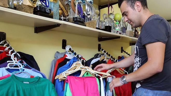 Un joven selecciona pantalón y camiseta en una tienda de ropa de peñas.
