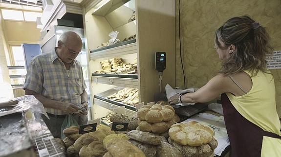 Una mujer atiende a un cliente en una panadería.
