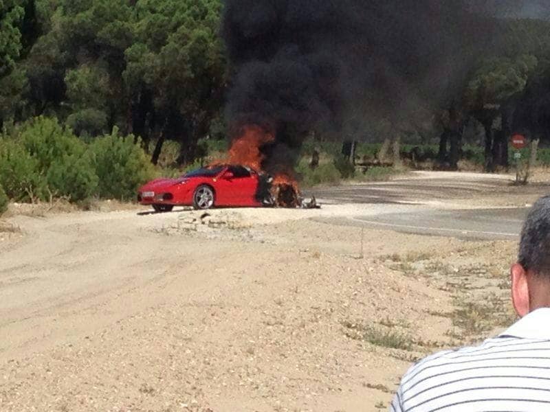 El Ferrari ardiendo junto a la carretera.