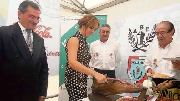 La consejera de Agricultura y Ganadería, Silvia Clemente, corta unas raciones de jamón, ayer, durante su visita a la feria.