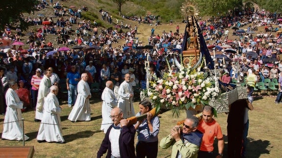 Los devotos aguardan, protegiéndose del sol con paraguas, el comienzo de la misa.