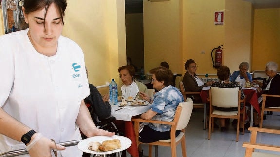 Una trabajadora sirve la comida a los residentes.