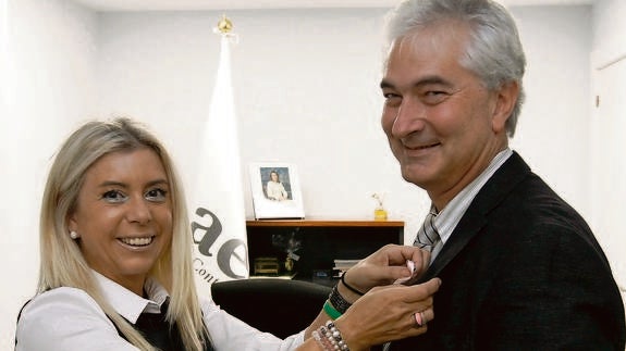 Inmaculada Rodríguez, presidenta de la Asociación Española Contra el Cáncer coloca un lazo rosa al investigador Atanasio Pandiella. 