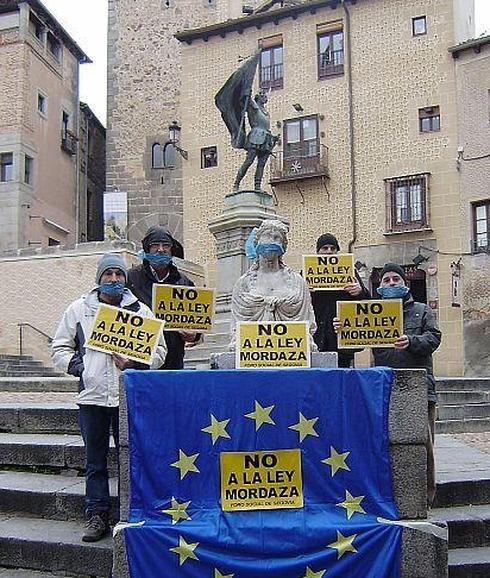 Cuatro miembros del Foro Social de Segovia, en la acción de protesta en la plaza de Medina del Campo.