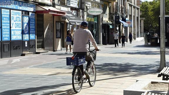 Un hombre pasea en bici este verano por el Paseo de Zorrilla. 