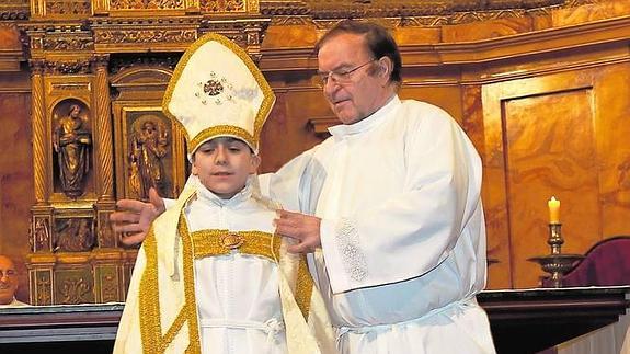 El director de Niños de Coro, Jesús Escudero, coloca la capa al obispillo. 