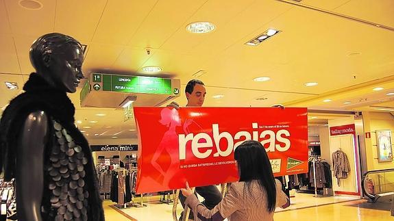 Instalación de un cartel de rebajas en El Corte Inglés. 
