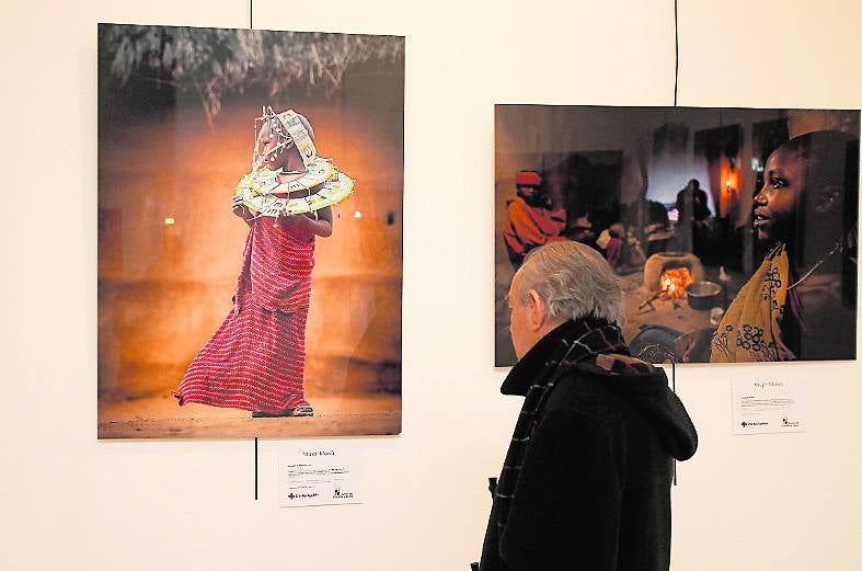 Un visitante contempla a una joven masái ornamentada.