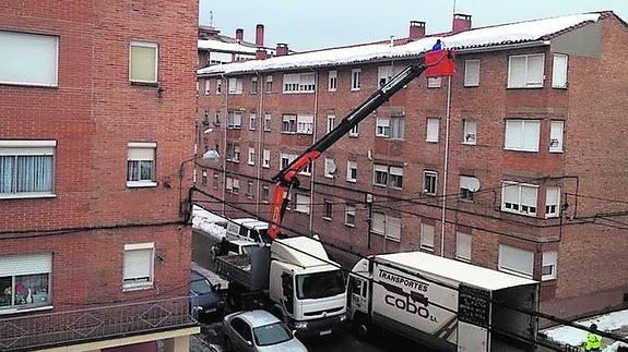 Un trabajador retira nieve de un tejado de las Casas del Hogar. 