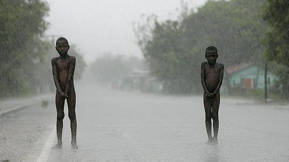 Dos niños permanecen desnudos bajo la intesa lluvia tras el paso del huracán 'Dean' por la República Dominicana el 19 de agosto de 2007.