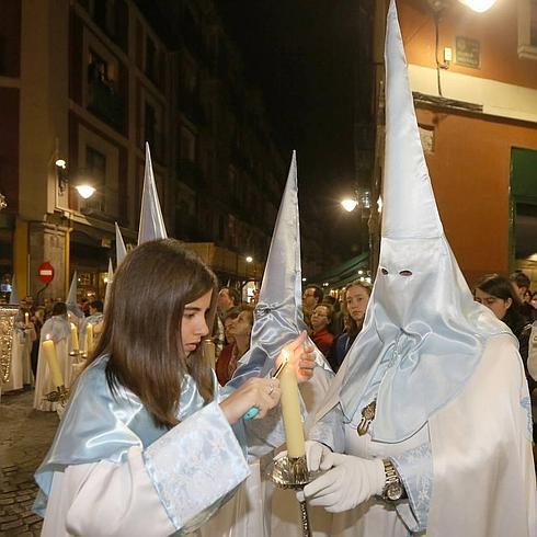 Una joven enciende la vela de otro cofrade en la Procesión de la Peregrinación de la Promesa del pasado año. 