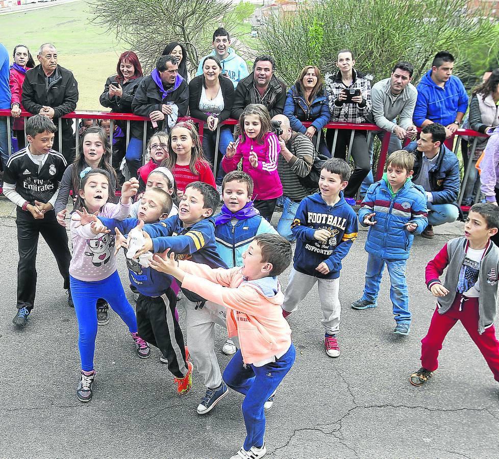 Varios pequeños con los brazos en alto intentan atrapar una bolsa. 