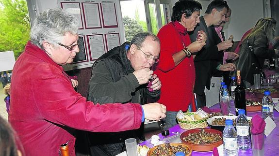 Miembros del jurado del concurso de guiso de caracoles degustan los quince platos presentados antes de emitir su veredicto.