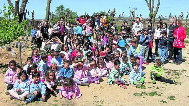 Fotografía de familia de todos los alumnos y profesores del Colegio de Educación Infantil y Primaria de Villoria, junto a los huertos que cultivan. 