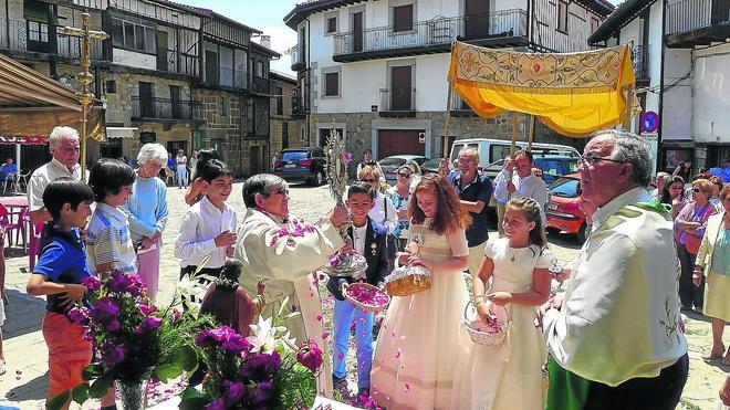 Un momento de la celebración en Sequeros, justo cuando los niños de Primera Comunión echan pétalos a la Custodia sujetada por el párroco. 