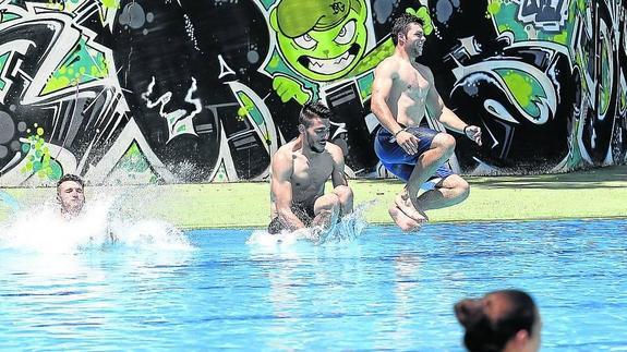 Tres jóvenes se divierten tirándose al agua, en las piscinas del Sotillo.