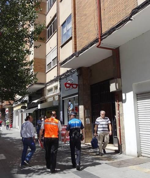 Los forenses, acompañados por un policía local, se dirigen al portal del número 5 de la calle Cigüeña, donde fue hallado el cuerpo. 