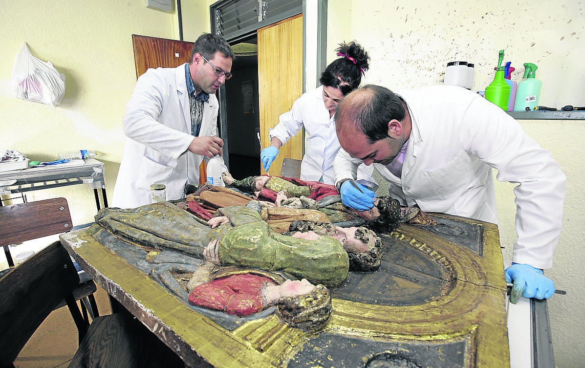 Tres restauradores intervienen en un relieve policromado en el taller temporal del año pasado. 