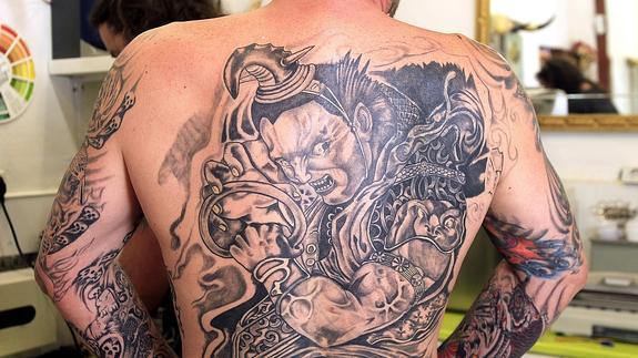 Espalda y brazos de un hombre con un gran tatuaje.