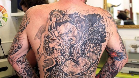 Espalda y brazos de un hombre con un gran tatuaje. 