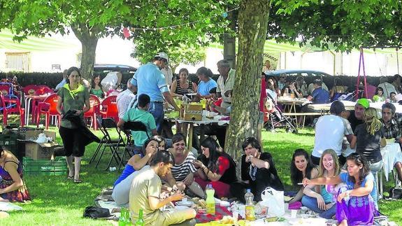Vecinos y visitantes disfrutan de una comida en la pradera de Báscones de Ojeda en las fiestas.