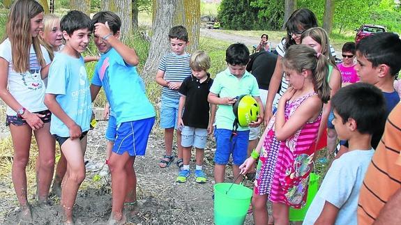 Algunos participantes pisan el barro y la paja para hacer los adobes.
