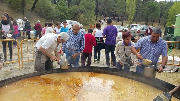 Varios vecinos recogen su ración de caldereta de patatas con carne, ayer en La Miguela. 