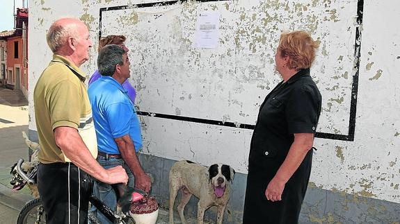 Vecinos de Mantinos leen ayer el bando municipal que recoge la prohibición de beber agua del grifo.